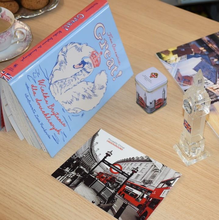 Na stole książka i pamiątki z Wielkiej Brytanii: pocztówka, figurka Big Bena